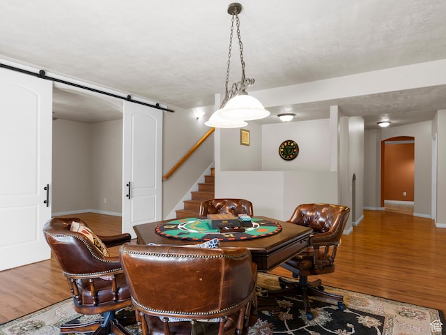 playroom featuring baseboards, arched walkways, a barn door, and wood finished floors