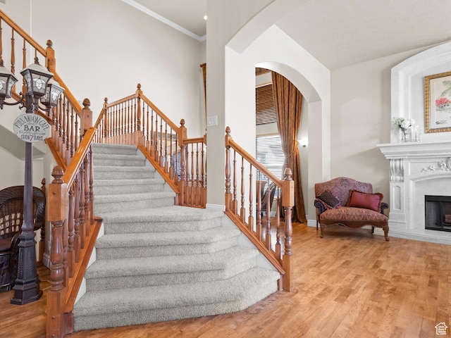 stairway featuring baseboards, arched walkways, wood finished floors, and a fireplace