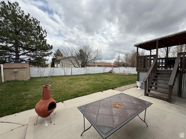 view of patio / terrace with stairway, a fenced backyard, an outdoor structure, and a storage unit