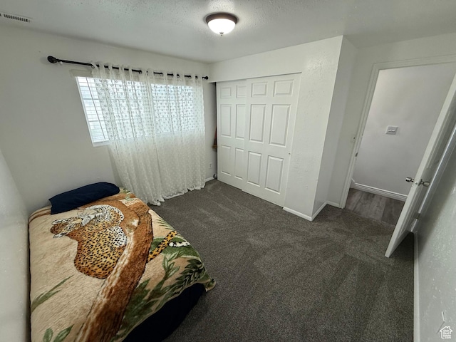 bedroom featuring dark colored carpet, a closet, baseboards, a textured ceiling, and visible vents