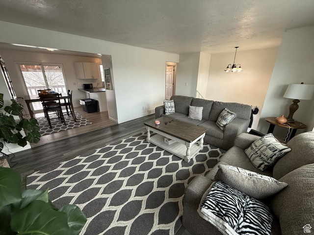 living room featuring baseboards, a chandelier, wood finished floors, and a textured ceiling