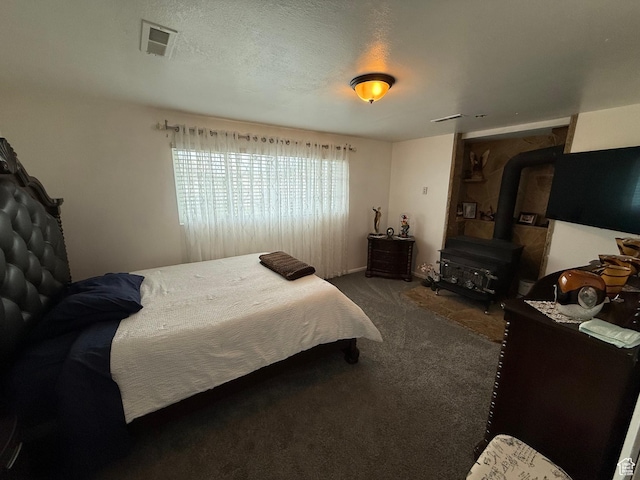 carpeted bedroom with a wood stove, visible vents, and a textured ceiling