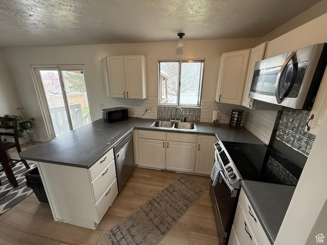 kitchen with a sink, appliances with stainless steel finishes, a peninsula, and a healthy amount of sunlight