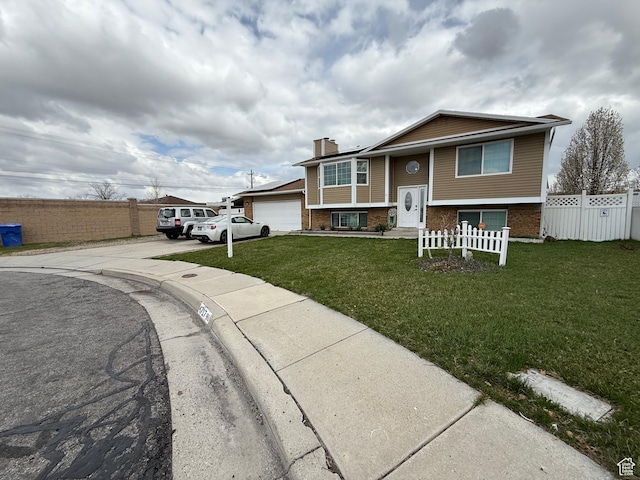 bi-level home with driveway, fence, a chimney, and a front lawn