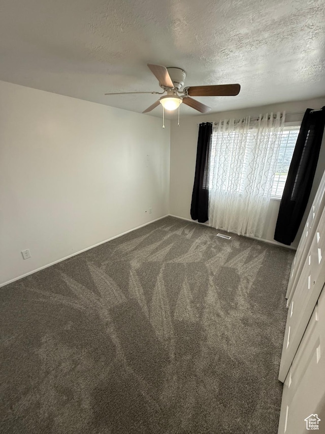 unfurnished room with carpet floors, a ceiling fan, visible vents, and a textured ceiling