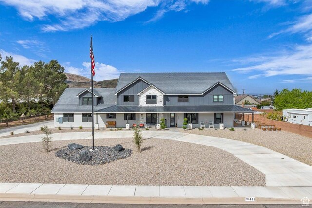 modern farmhouse style home with covered porch, fence, and stone siding