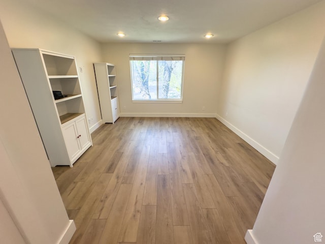 empty room with light wood-style floors, baseboards, and recessed lighting