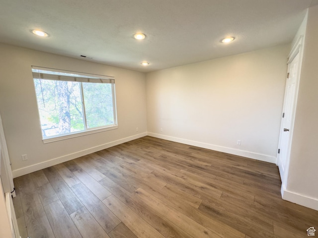 unfurnished room with wood finished floors, baseboards, visible vents, and recessed lighting