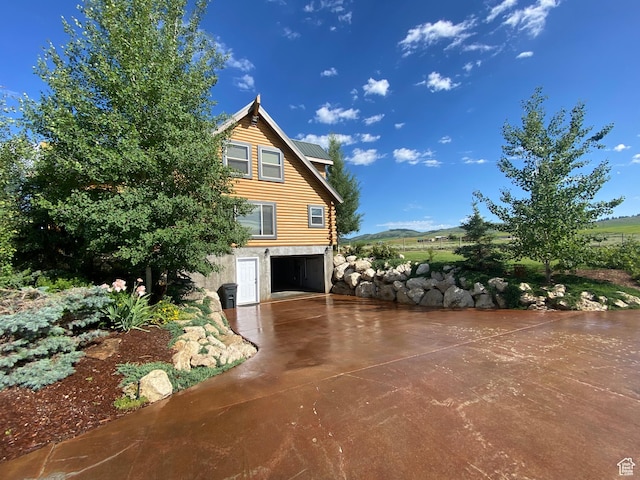 view of side of property featuring log siding, a garage, and driveway