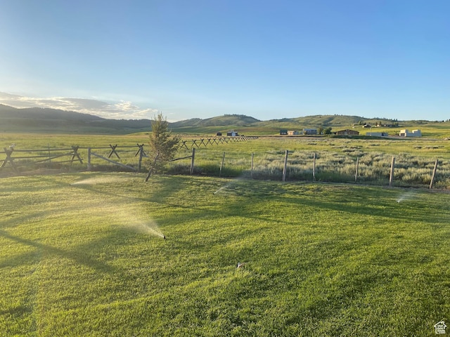 view of yard with a rural view, a mountain view, and fence