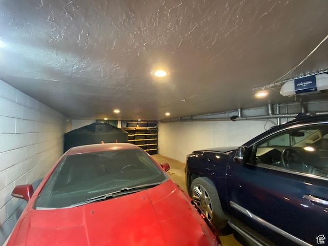 garage featuring concrete block wall and a garage door opener
