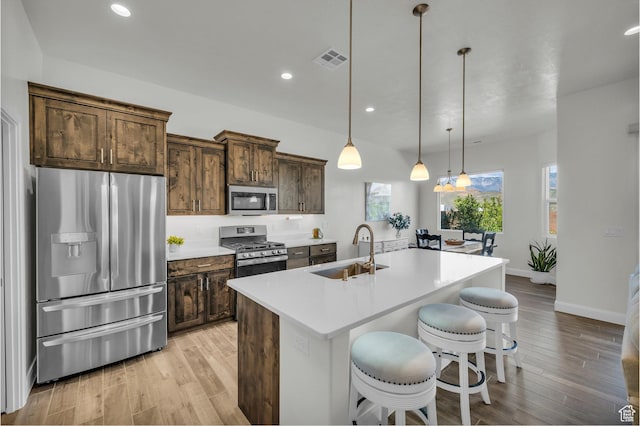 3086 W 570 N, Hurricane, UT 84737 - kitchen with visible vents, a sink, a kitchen island with sink, light wood finished floors, and stainless steel appliances