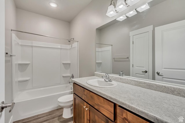 bathroom with toilet, wood finished floors, vanity, and bathing tub / shower combination