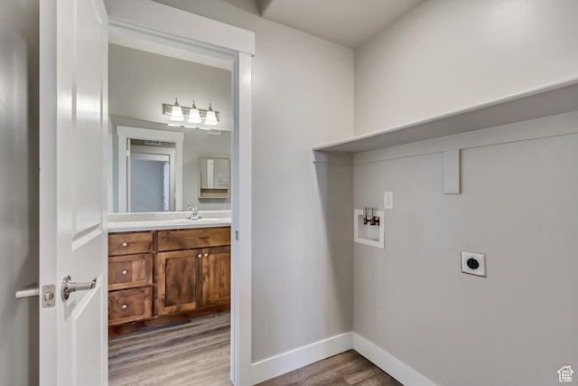 laundry room with laundry area, hookup for a washing machine, electric dryer hookup, light wood-type flooring, and baseboards