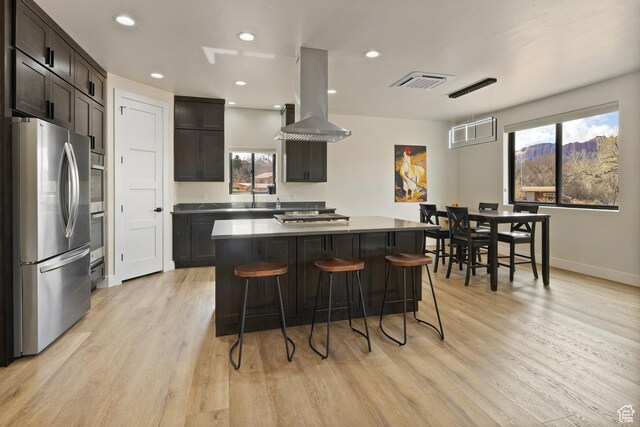 kitchen featuring light wood-style flooring, visible vents, a breakfast bar, stainless steel appliances, and island range hood