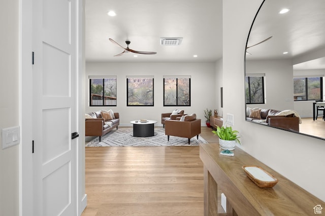 living room featuring light wood-style flooring, ceiling fan, visible vents, and recessed lighting