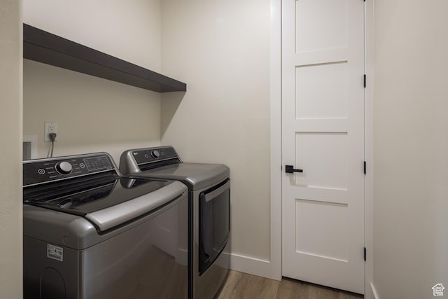 laundry area featuring independent washer and dryer, wood finished floors, laundry area, and baseboards