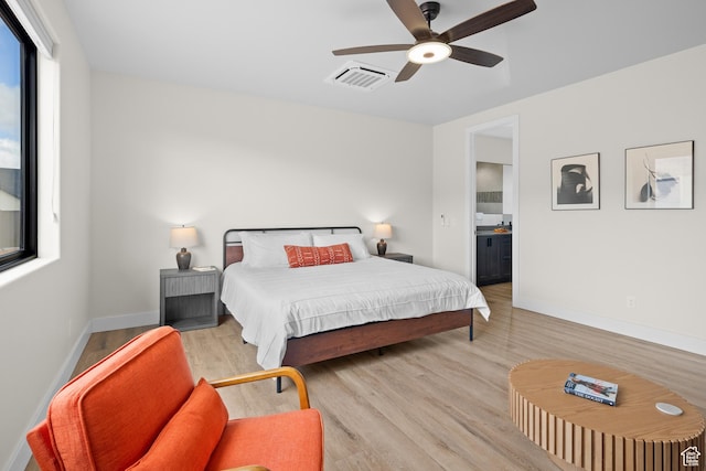 bedroom featuring ensuite bath, visible vents, baseboards, and wood finished floors