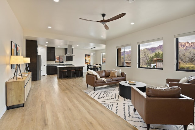 living area with recessed lighting, light wood-type flooring, and a ceiling fan