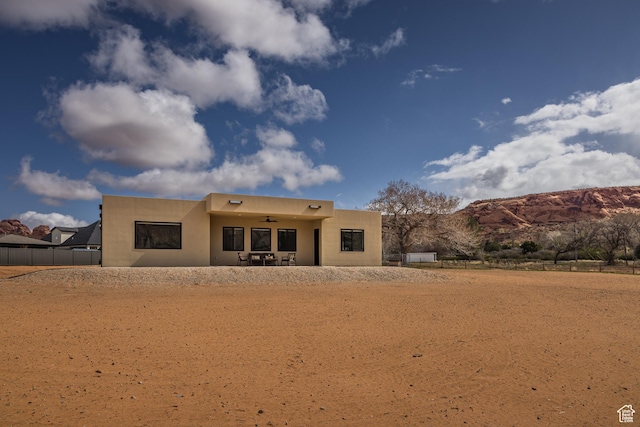 rear view of property featuring a mountain view, fence, and a ceiling fan