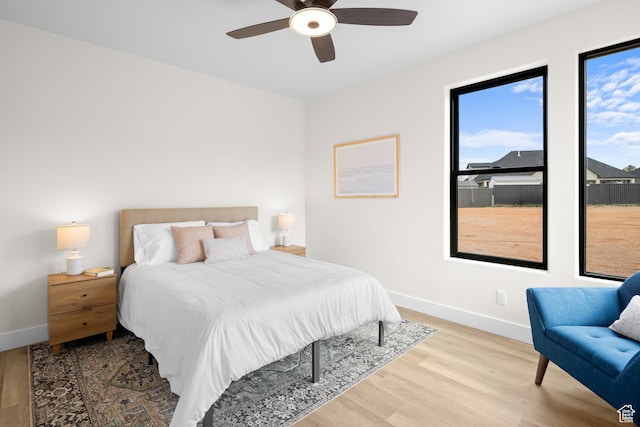 bedroom with ceiling fan, baseboards, and wood finished floors
