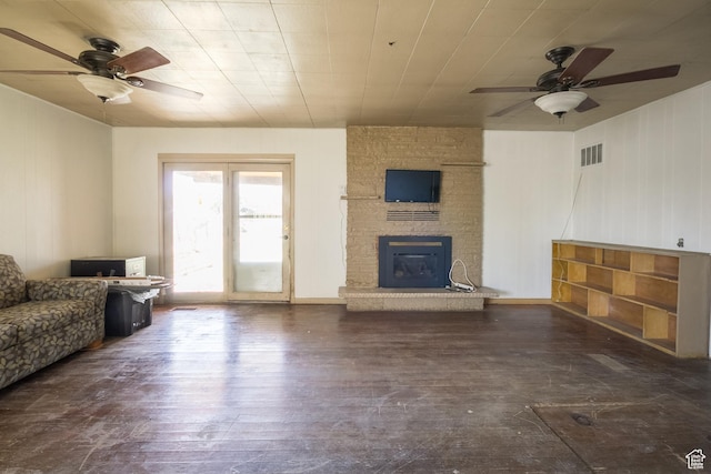 living area with visible vents, hardwood / wood-style flooring, a ceiling fan, and a large fireplace