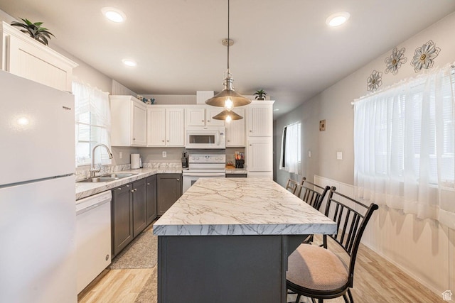 1150 W Red Hills Pkwy Unit 57, Washington, UT 84780 - kitchen with white appliances, light countertops, a center island, white cabinetry, and a sink