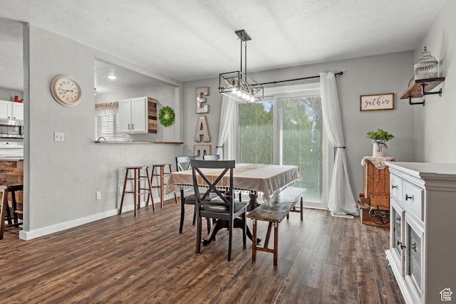 dining area with dark wood-type flooring, baseboards, and a textured ceiling