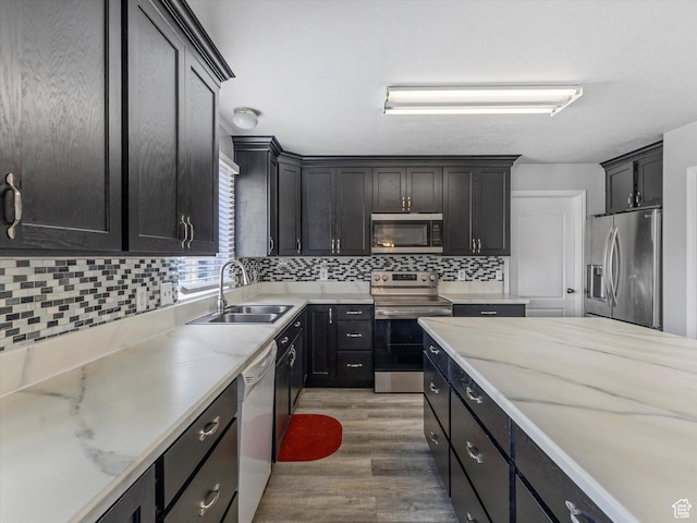 4572 W Bingham Park Dr S, West Jordan, UT 84088 - kitchen featuring light stone counters, wood finished floors, a sink, stainless steel appliances, and backsplash