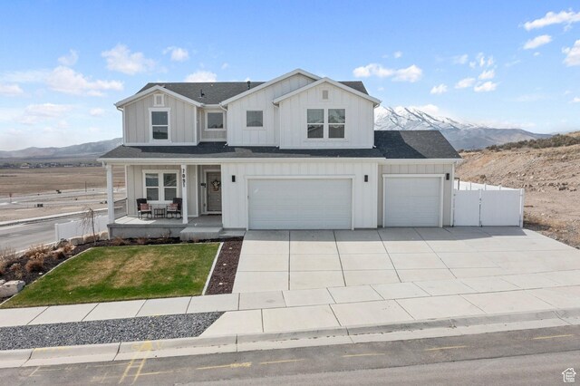 7091 N Oquirrh Ranch Pkwy, Eagle Mountain, UT 84005 - view of front of property with a porch, a garage, board and batten siding, fence, and concrete driveway