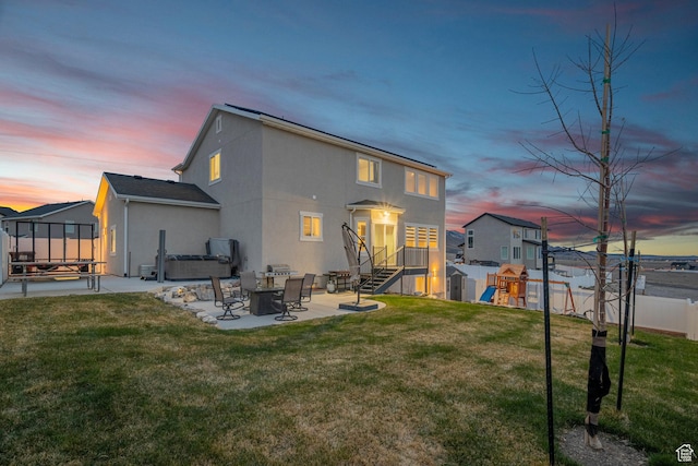 7091 N Oquirrh Ranch Pkwy, Eagle Mountain, UT 84005 - back of house at dusk with a patio, stucco siding, a playground, and a yard