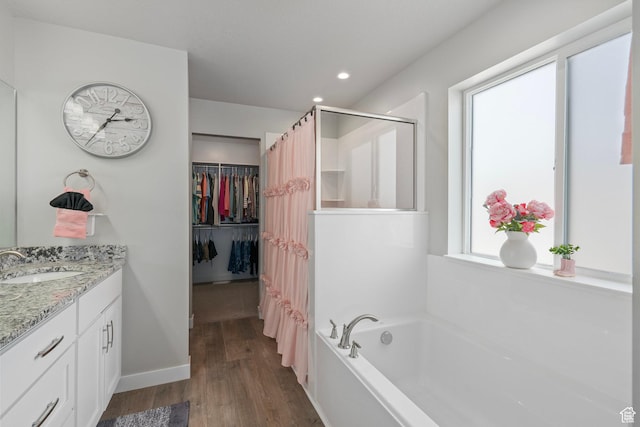 7091 N Oquirrh Ranch Pkwy, Eagle Mountain, UT 84005 - full bath featuring vanity, a spacious closet, a shower stall, a garden tub, and wood finished floors