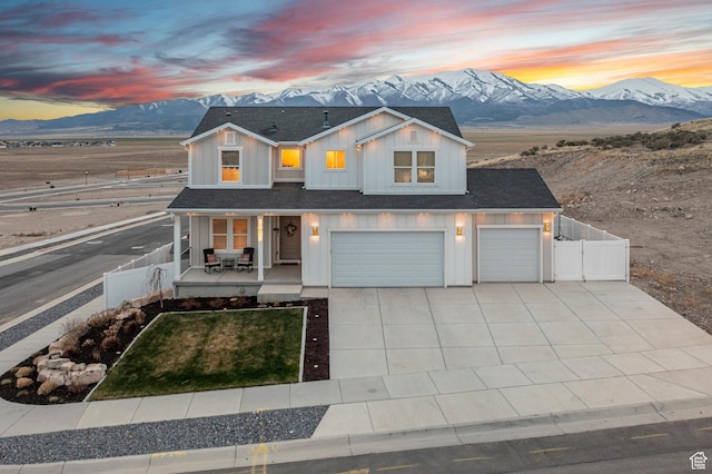 7091 N Oquirrh Ranch Pkwy, Eagle Mountain, UT 84005 - view of front facade with board and batten siding, a porch, fence, an attached garage, and a mountain view