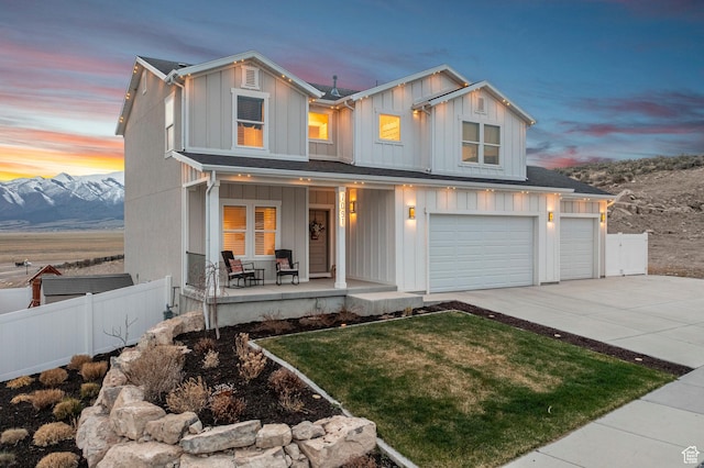 7091 N Oquirrh Ranch Pkwy, Eagle Mountain, UT 84005 - view of front facade with board and batten siding, covered porch, fence, an attached garage, and driveway