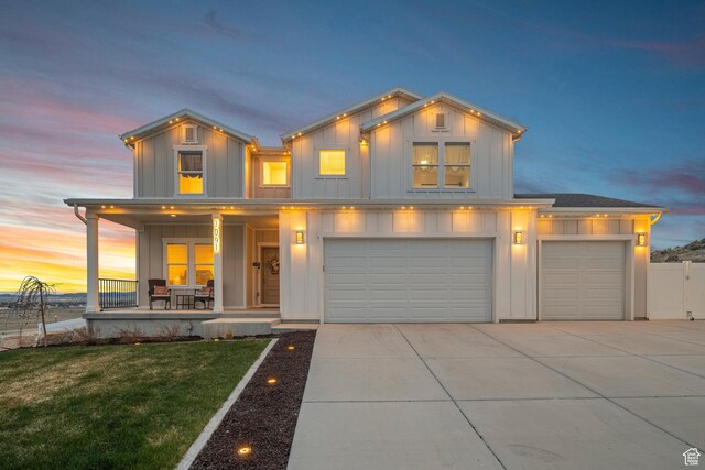 7091 N Oquirrh Ranch Pkwy, Eagle Mountain, UT 84005 - view of front facade featuring covered porch, a lawn, a garage, board and batten siding, and concrete driveway