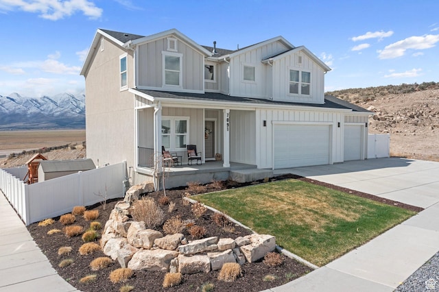view of front of home featuring board and batten siding, a porch, fence, an attached garage, and driveway