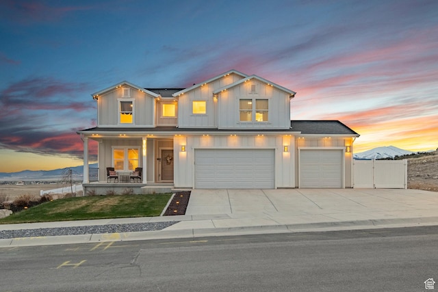 7091 N Oquirrh Ranch Pkwy, Eagle Mountain, UT 84005 - view of front of home featuring concrete driveway, board and batten siding, a garage, a gate, and covered porch