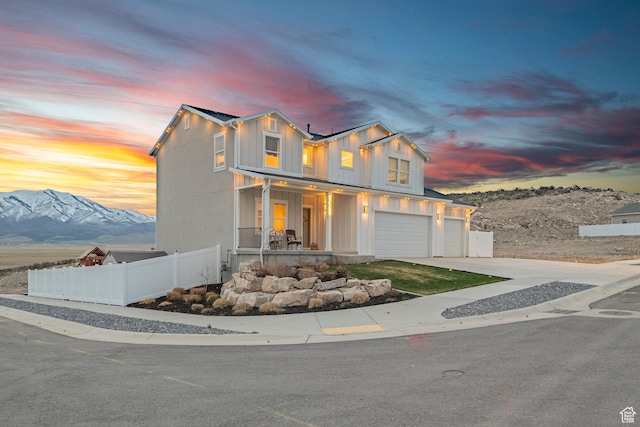 7091 N Oquirrh Ranch Pkwy, Eagle Mountain, UT 84005 - view of front facade with concrete driveway, board and batten siding, an attached garage, a porch, and fence