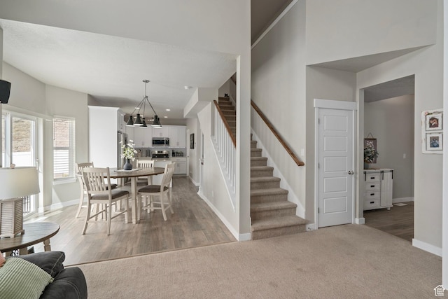 7091 N Oquirrh Ranch Pkwy, Eagle Mountain, UT 84005 - dining area featuring light carpet, stairway, a notable chandelier, and baseboards