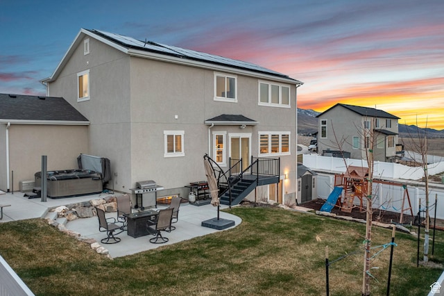 7091 N Oquirrh Ranch Pkwy, Eagle Mountain, UT 84005 - back of property at dusk featuring a fenced backyard, a patio, a lawn, and a hot tub