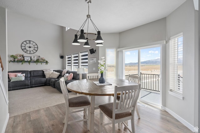 7091 N Oquirrh Ranch Pkwy, Eagle Mountain, UT 84005 - dining space featuring a chandelier, light wood finished floors, baseboards, and a textured ceiling