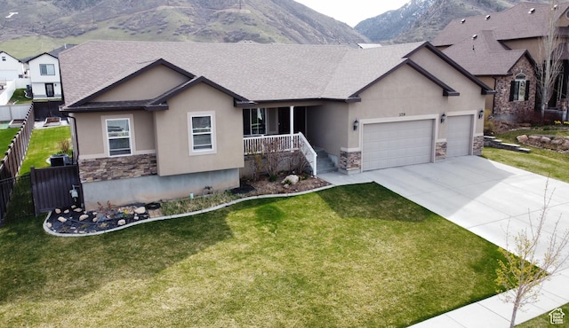 single story home with a mountain view, an attached garage, stone siding, and stucco siding