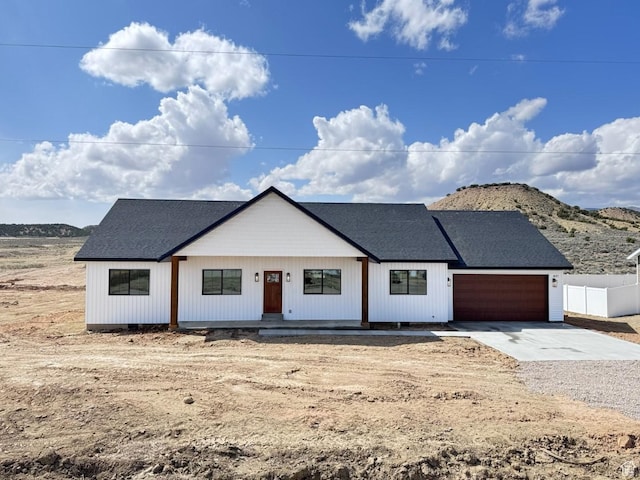 modern farmhouse style home featuring an attached garage, fence, driveway, and roof with shingles