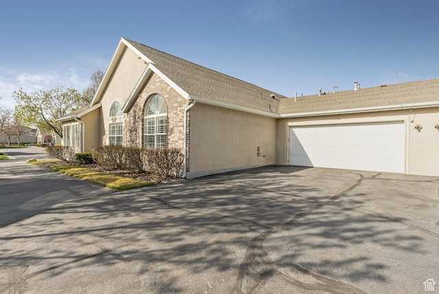 view of property exterior featuring aphalt driveway, an attached garage, and stucco siding