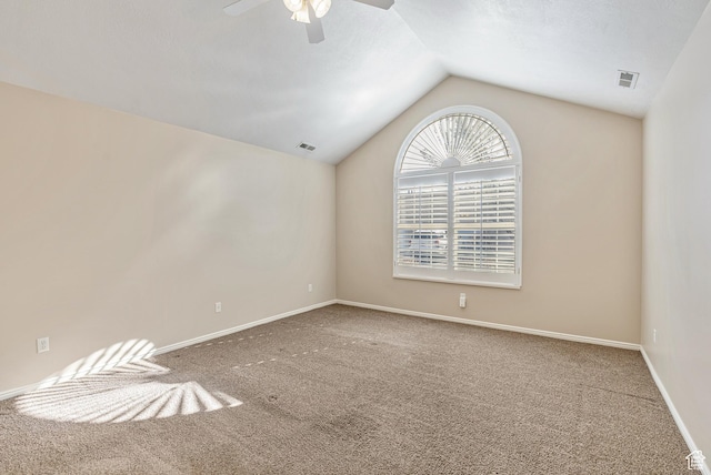 carpeted spare room with baseboards, visible vents, vaulted ceiling, and a ceiling fan