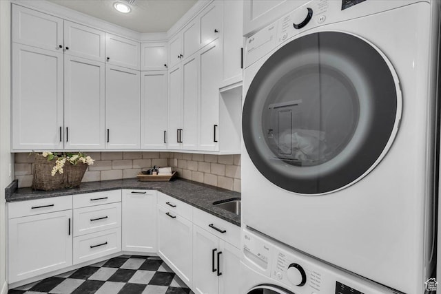 laundry room with cabinet space, stacked washer and clothes dryer, dark floors, and recessed lighting