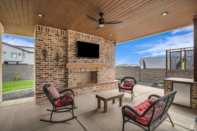 view of patio / terrace featuring a fenced backyard, an outdoor living space with a fireplace, and ceiling fan