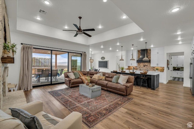 living area featuring light wood-style flooring, ceiling fan, visible vents, and recessed lighting