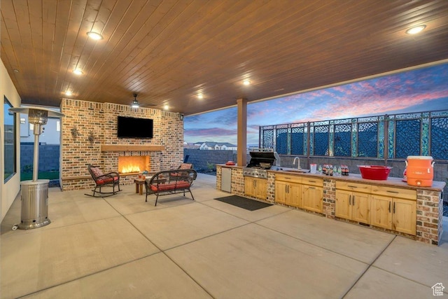 view of patio featuring fence, grilling area, area for grilling, a sink, and an outdoor brick fireplace