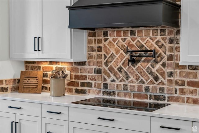 kitchen with white cabinets, custom exhaust hood, black electric stovetop, and light stone counters